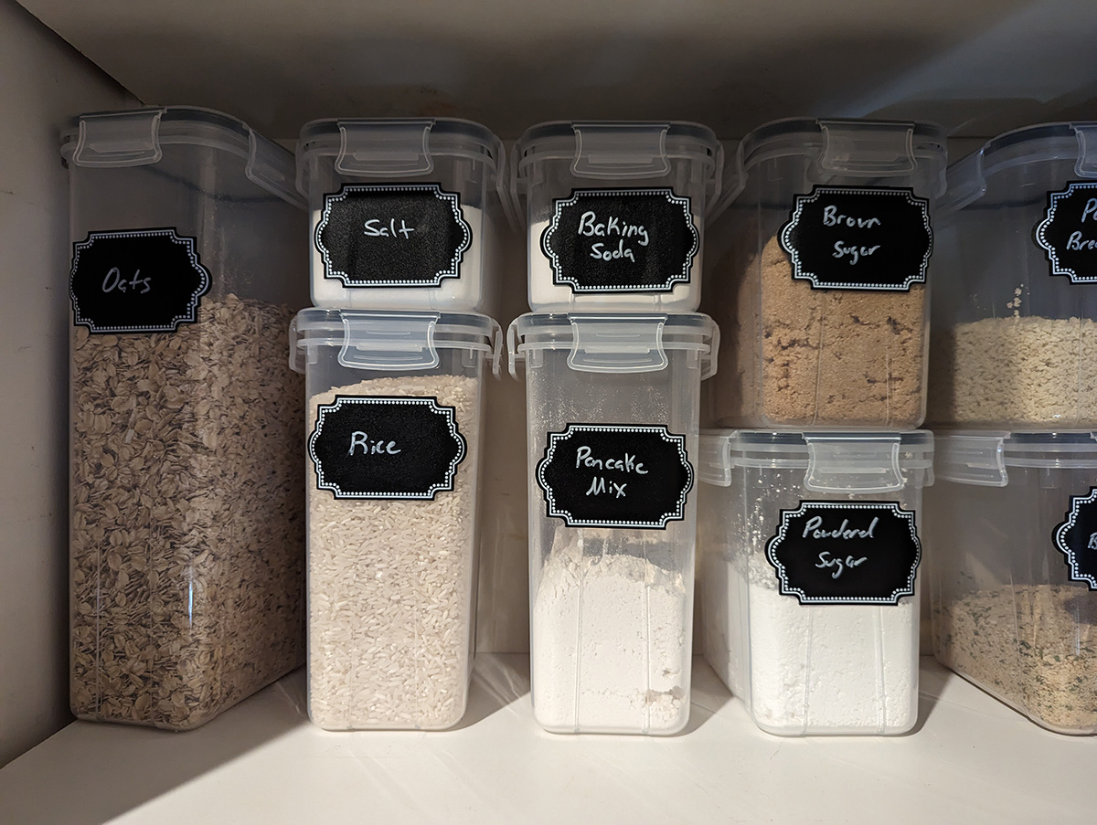 A cabinet filled with clear organizational tubs with cooking supplies